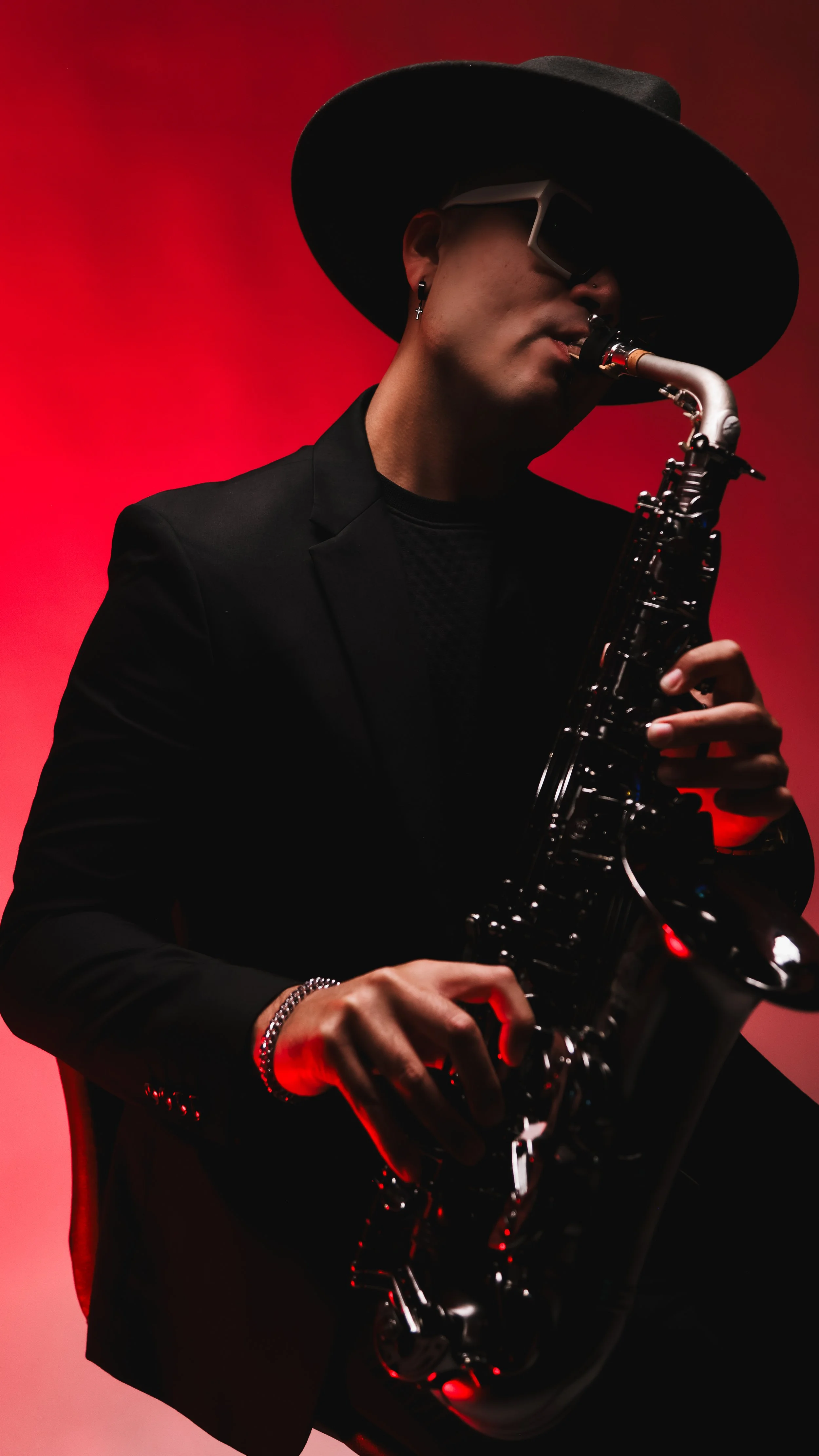 Philip Mahoney performing on saxophone in a black suit and hat